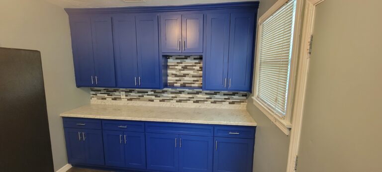 Custom blue shaker kitchen cabinets with marble countertops and decorative tile backsplash