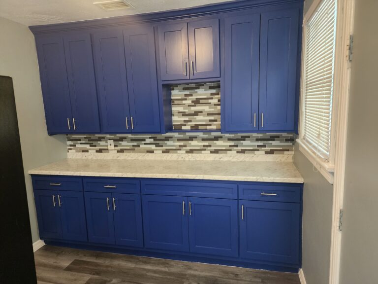 Close-up of custom blue shaker kitchen cabinets with marble countertops and modern cabinet hardware in Jacksonville, FL